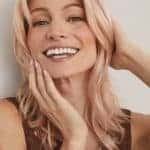 Woman with blonde wavy wig smiling, showcasing natural hair texture and style.
